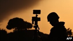 A member of the media stands behind his camera at a spot overlooking the Gaza Strip in the southern Israeli city of Sderot, Oct. 26, 2023, amid ongoing battles between Israel and the Palestinian Hamas movement.