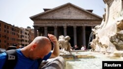 Seorang pria mendinginkan diri di air mancur dekat Pantheon, saat gelombang panas melanda Italia, di Roma, 19 Juli 2023. (Foto: Reuters)