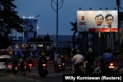 Masyarakat berjalan melewati baliho Menteri Pertahanan dan calon Presiden Prabowo Subianto dan pasangannya Gibran Rakabuming Raka di Jakarta, 12 Januari 2024. (Foto: REUTERS/Willy Kurniawan)