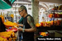 A worker at the Erawan Shrine in Bangkok cool down by standing by an electric fan and eating ice-pops in Bangkok, Thailand, April 23, 2023.