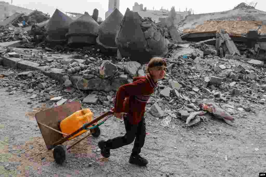 A child carries a jerrycan of water as he walks in front of the Al-Faruq mosque, leveled by Israeli bombardment in Rafah in the southern Gaza Strip on a foggy day, Feb. 25, 2024.