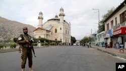 Taliban fighters stand guard as Afghan people attend Eid al-Adha prayers, in Kabul, Afghanistan, June 28, 2023. 