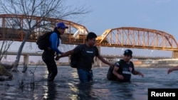 Seorang perempuan dari Guatemala (kiri) bersama migran lainnya menyeberangi sungai Rio Grande dari Piedras Negras di Meksiko untuk mencapai Eagle Pass, Texas, pada 24 Februari 2024. (Foto: Reuters/Cheney Orr)