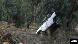 A member of the public walks near a tipped car among damage from the overnight flooding of the Porto River after Storm Ciaran hit the region, at the port of Porto, on the French Mediterranean island of Corsica, Nov. 3, 2023. 