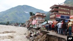 People stand by a road washed away by the River Beas swollen due to heavy rains in Kullu District, Himachal Pradesh, India, July 11, 2023. Heavy monsoon rains caused landslides and flash floods in the country's north. 