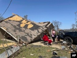Orang-orang duduk di depan rumah mereka yang hancur diterjang badai tornado di Silver City, Sabtu, 25 Maret 2023. (Foto: Michael Goldberg/AP Photo)