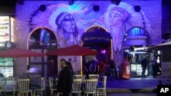 FILE - A couple strolls past the Coyote nightclub in Lleras Park in Medellin, Colombia,Feb. 2, 2024.
