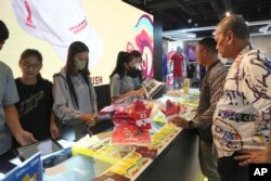 Petugas toko melayani pelanggan yang berbelanja merchandise resmi FIFA U-20 World Cup di sebuah pusat perbelanjaan di Jakarta, Jumat, 31 Maret 2023. (Foto: AP)