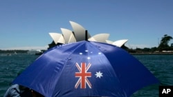 资料照 - 澳大利亚国庆日，悉尼港一位妇女撑开印有澳大利亚国旗图案的遮阳伞。