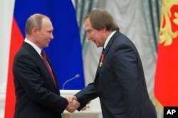 FILE - Presiden Rusia Vladimir Putin (kiri), memberikan medali kepada pemain cello Rusia Sergei Roldugin, dalam upacara penghargaan di Kremlin Moskow, Rusia, Kamis, 22 September 2016. (AP/Ivan Sekretarev, Pool, File)