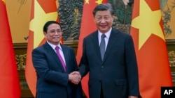FILE - Vietnam's Prime Minister Pham Minh Chinh , left, shakes hands with Chinese President Xi Jinping before their meeting in Beijing, June 27, 2023. Xi is expected to pay a state visit to Vietnam this week.