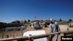 Seorang warga Palestina tampak memindahkan tangki air di desa Umm Al-Khair di Tepi Barat, di saat para pemukim Israel merangsek desa tersebut pada 7 Februari 2017. (Foto: Reuters/Mussa Qawasma)
