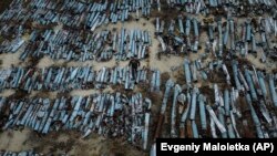 A war prosecutor observes collected parts of Russian rockets used to attack the city of Kharkiv on December 22, 2022. (Evgeniy Maloletka/AP)
