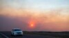 Автомобил во движење на патот кон Розвел, Њу Мексико, додека чадот од шумски пожар делумно го блокира сонцето во близина на селото Руидосо, 18 јуни 2024 година.
