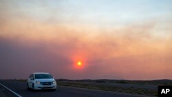 Автомобил во движење на патот кон Розвел, Њу Мексико, додека чадот од шумски пожар делумно го блокира сонцето во близина на селото Руидосо, 18 јуни 2024 година.