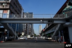 People cross an almost empty street during a "silent strike" to protest and mark the third anniversary of the military coup in Yangon, Myanmar, Feb. 1, 2024.