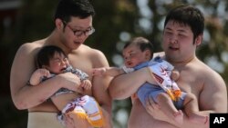 แฟ้ม - นักซูโม่อุ้มเด็กน้อยระหว่างการแข่งขัน Naki Sumo หรือการแข่งขันร้องไห้ของเด็กทารก ที่วัดเซนโซจิ ในกรุงโตเกียว เมื่อ 26 เม.ย. 2015 (เอพี)