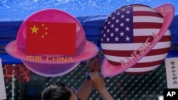 Seorang pedagang menjual makanan dan minuman di stan bertema planet berbentuk bendera China dan Amerika selama Karnaval Musim Semi di Beijing, 13 Mei 2023. (Foto: AP)
