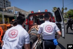 Israeli paramedics evacuate an injured man at the site of a Palestinian car-ramming attack at a bus stop in Tel Aviv, Israel, July 4, 2023.