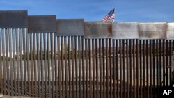 FILE - A US flag flies behind the border fence that divides Mexico and the US, in Tijuana, Mexico, Nov. 21, 2018.