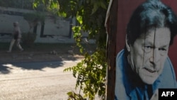 A woman walks past a poster of Pakistan's former prime minister Imran Khan near his Banigala residence, in Islamabad, Dec. 23, 2023. 