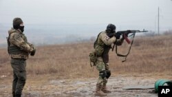 FILE - A Russian army soldier shoots as an instructor stands near during a practice on a military training ground in Russian-controlled Donetsk region, eastern Ukraine, Jan. 31, 2023.