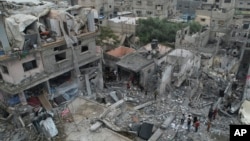 Palestinians walk about buildings destroyed in the Israeli bombardment in the Nusseirat refugee camp in the Gaza Strip, Oct. 29, 2023. 
