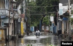 A man rides a motorcycle through a waterlogged street in Mandvi before the arrival of Cyclone Biparjoy in the western state of Gujarat, India, June 15, 2023.