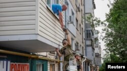 Serhii, a local resident who lives in a flooded house, receives humanitarian aid after the Nova Kakhovka dam breached, amid Russia's attack on Ukraine, in Kherson, Ukraine, June 7, 2023. 