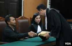 Kuasa hukum tersangka memberikan uang bantuan sebesar 200 juta rupiah kepada ayah Siti Khotimah, Suparna (kiri) dalam sidang putusan tindak kekerasan majikan terhadap PRT di Pengadilan Negeri Jakarta Selatan, Senin (24/7) sore. (VOA/Indra Yoga)
