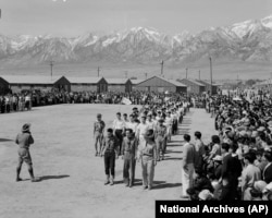 FILE - In this photo provided by the National Archives, Japanese Americans, including American Legion members and Boy Scouts, participate in Memorial Day services at the Manzanar Relocation Center, an internment camp in Manzanar, Calif., May 31, 1942.