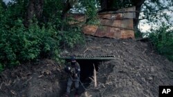 FILE - An armed tribal Kuki walks out of an underground bunker at a de facto front line dissecting two ethnic zones in Churachandpur, in the Indian state of Manipur, June 20, 2023.