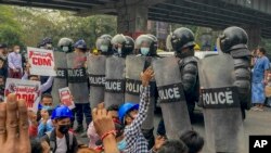 Demonstran memprotes kudeta militer di depan polisi anti huru hara di Yangon, Myanmar, Kamis, 18 Februari 2021. (Foto: AP)