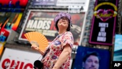 A tour guide fans herself while working in Times Square as temperatures rise, July 27, 2023, in New York.