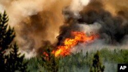 FILE - Flames from the Donnie Creek wildfire burn along a ridge top north of Fort St. John, British Columbia, Canada, July 2, 2023. 