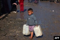 Seorang anak laki-laki membawa jerigen kosong di Rafah di Jalur Gaza selatan di tengah pertempuran antara Israel dan kelompok Hamas Palestina, 3 Februari 2024. (Foto: AFP)