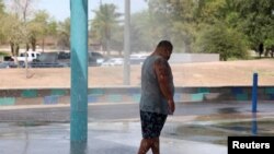 Seorang pria mendinginkan diri di taman air selama gelombang panas di Phoenix, Arizona, AS, 16 Juli 2023. (Foto: REUTERS/Liliana Salgado)