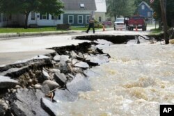 A passer-by walks near a street damaged by flood waters, in Ludlow, Vermont, July 11, 2023.