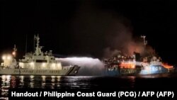 This handout picture taken on March 29, 2023 and released by the Philippine Coast Guard shows the Philippine Coast Guard spraying water on a fire onboard the Lady Mary Joy 3. (Photo by Handout / Philippine Coast Guard (PCG) / AFP)