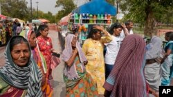 People cover their heads to shield from the heat as they buy water bottles in New Delhi, India, Tuesday, June 18, 2024.