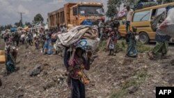 Un jeune garçon porte quelques-uns de ses biens alors que les gens fuient le territoire de Masisi suite aux affrontements entre les rebelles du M23 et les forces gouvernementales, sur une route près de Sake le 7 février 2024. (Photo par Aubin Mukoni / AFP)