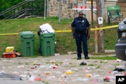 A police officer stands in the area of a mass shooting incident in the Southern District of Baltimore, July 2, 2023.