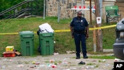 A police officer stands in the area of a mass shooting incident in the Southern District of Baltimore, July 2, 2023. 