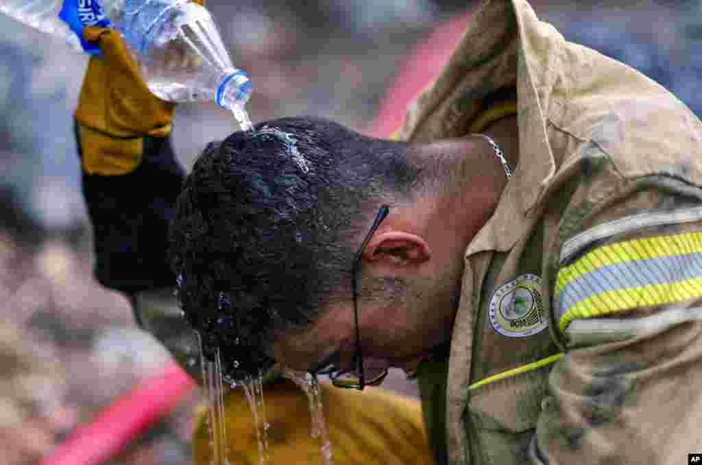 A firefighter cools himself with water while extinguishing a wildfire in Antalya, Turkey, July 25, 2023. 