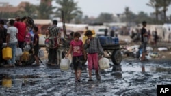 Palestinians gather to fill water jugs near one of the strip's few functioning desalination plants in Deir al-Balah, Gaza Strip, June 20, 2024.