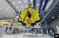 FILE - In this photo provided by NASA, technicians lift the mirror of the James Webb Space Telescope using a crane, at the Goddard Space Flight Center in Greenbelt, Maryland, April 13, 2017.