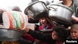 Палестинските деца чекаат да добијат храна зготвена од добротворна кујна во Рафа во јужниот дел на појасот Газа, на 13 февруари 2024 година