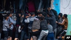 Warga Palestina kesulitan membeli roti dari toko roti di Rafah, Jalur Gaza, Minggu, 18 Februari 2024. (Foto: AP)