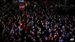 People sign "I love you" while gathered at a vigil for the victims of Wednesday's mass shootings, Oct. 29, 2023, outside the Basilica of Saints Peter and Paul in Lewiston, Maine.