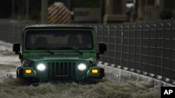 Sebuah SUV melewati genangan air di Dubai, Uni Emirat Arab, Selasa, 16 April 2024. Hujan lebat melanda Uni Emirat Arab pada hari Selasa, membanjiri sebagian jalan raya utama dan meninggalkan kendaraan terbengkalai di jalan raya melintasi Dubai. (AP/Jon Gambrell)